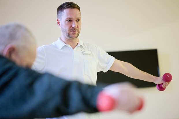 Eine Pflegefachkraft mit Hantel und ein Patient mit Hantel Eine Pflegefachkraft mit Hantel und ein Patient mit Hantel