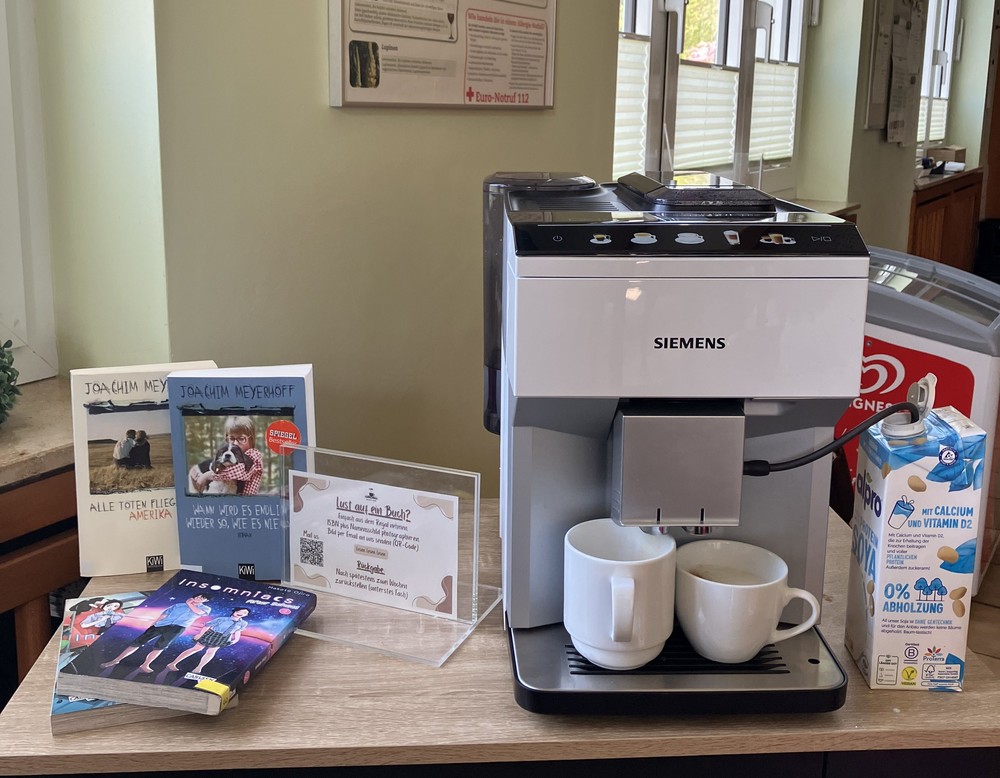 Mehrere Bücher liegen neben einem Kaffeevollautomaten