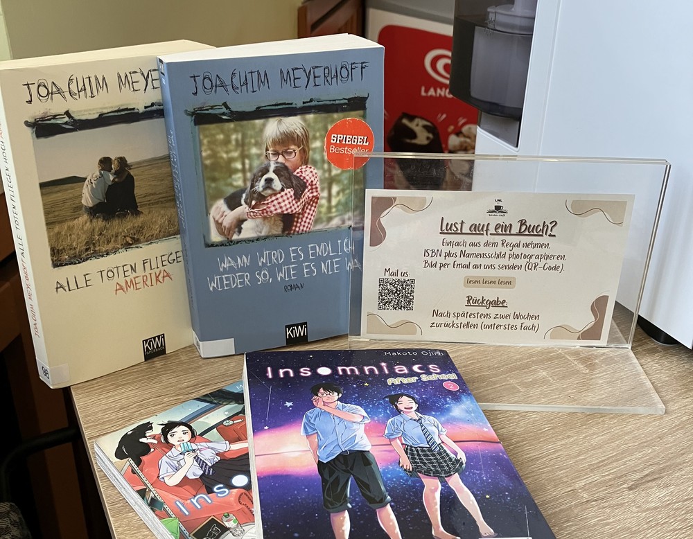 Mehrere Bücher und Infoschild auf einem Sideboard