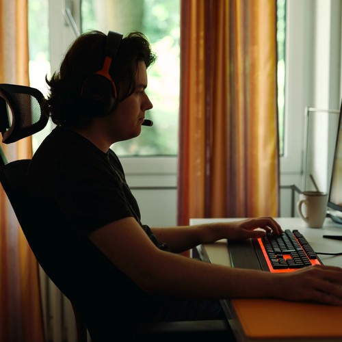 Ein Mann der an einem Schreibtisch sitzt und ein Computerspiel spielt.