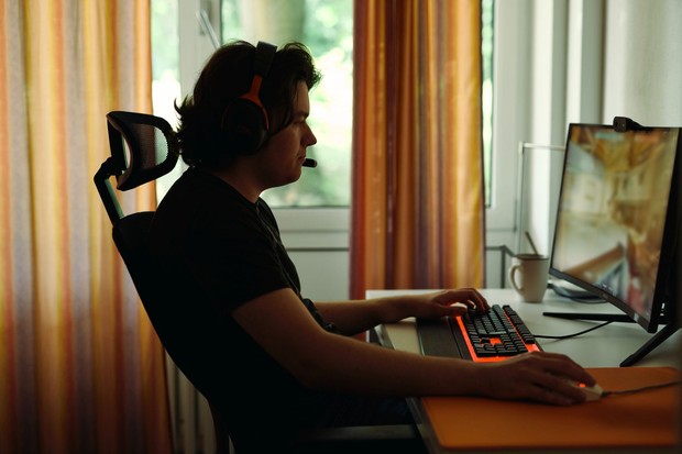 Ein Mann der an einem Schreibtisch sitzt und ein Computerspiel spielt.