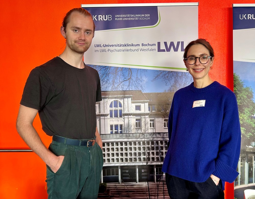 2 Menschen vor einem Plakat