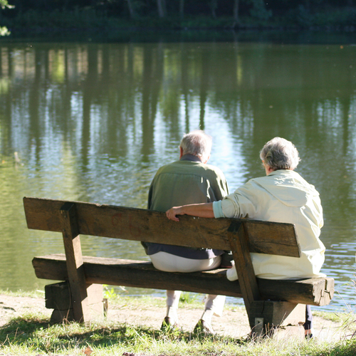 zwei Senioren auf einer Parkbank am Wasser