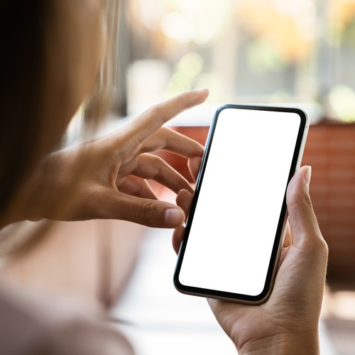 Smartphone mit hellem Display in den Händen einer Frau