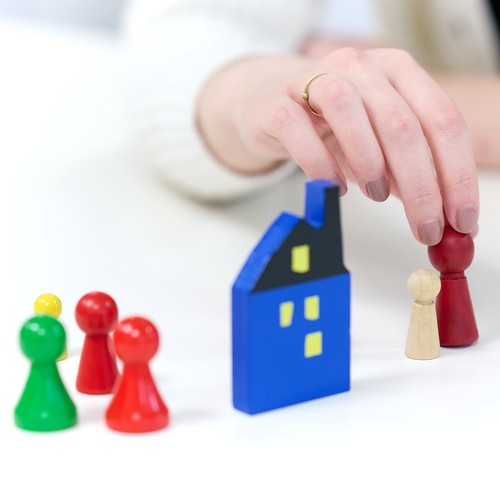 Hand setzt Figur bei Haus